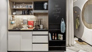 Une cuisine moderne avec des meubles blancs, un plan de travail noir et un tableau noir sur lequel est écrit un message.