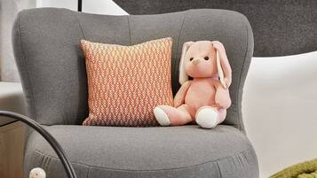 Ein modernes Wohnzimmer mit einer grauen Couch, einem kleinen Tisch mit einem Spielzeugauto und einem an der Wand befestigten Fernseher.