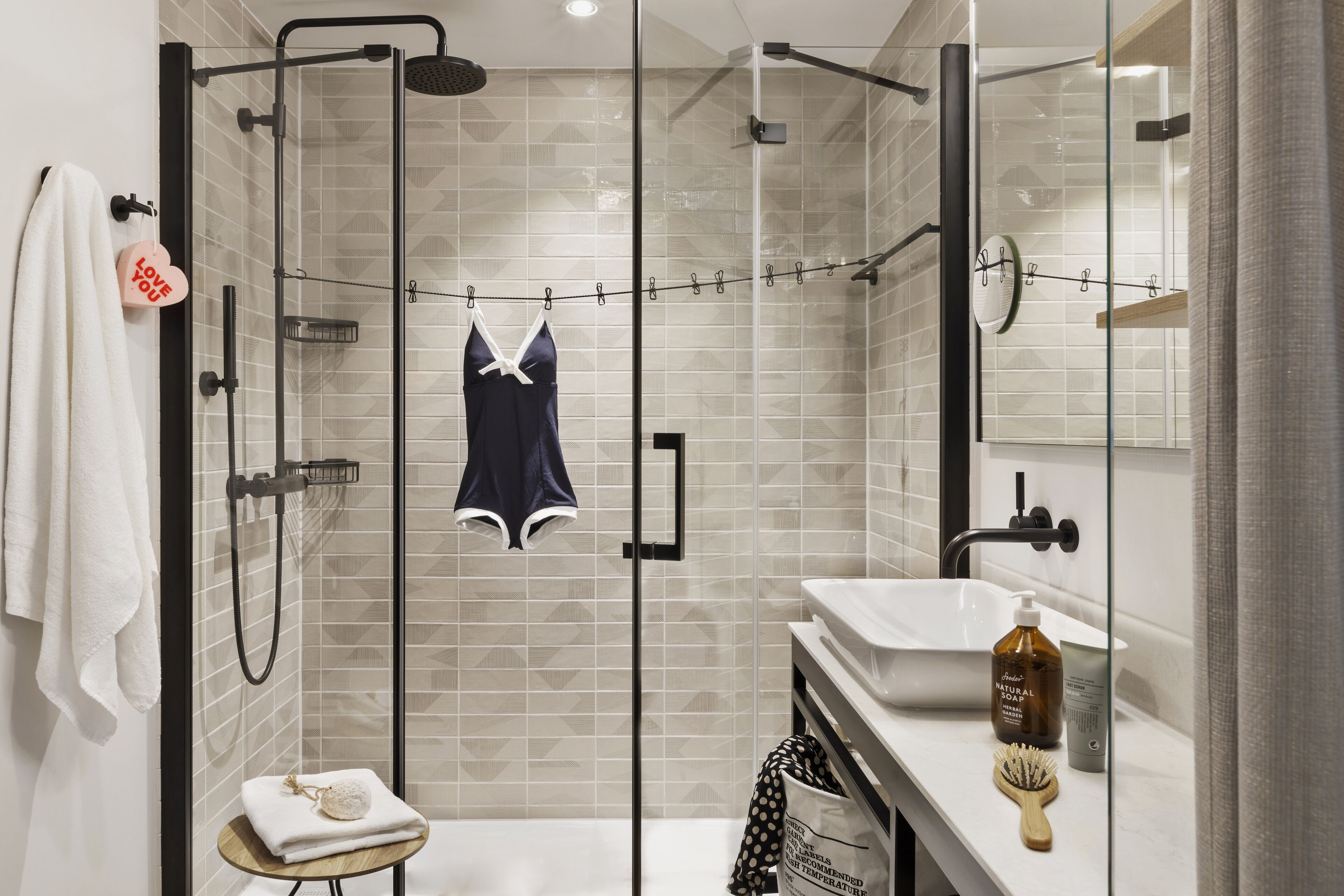 Une salle de bain moderne avec une douche à parois de verre, un lavabo blanc et un meuble-lavabo avec des articles de toilette.