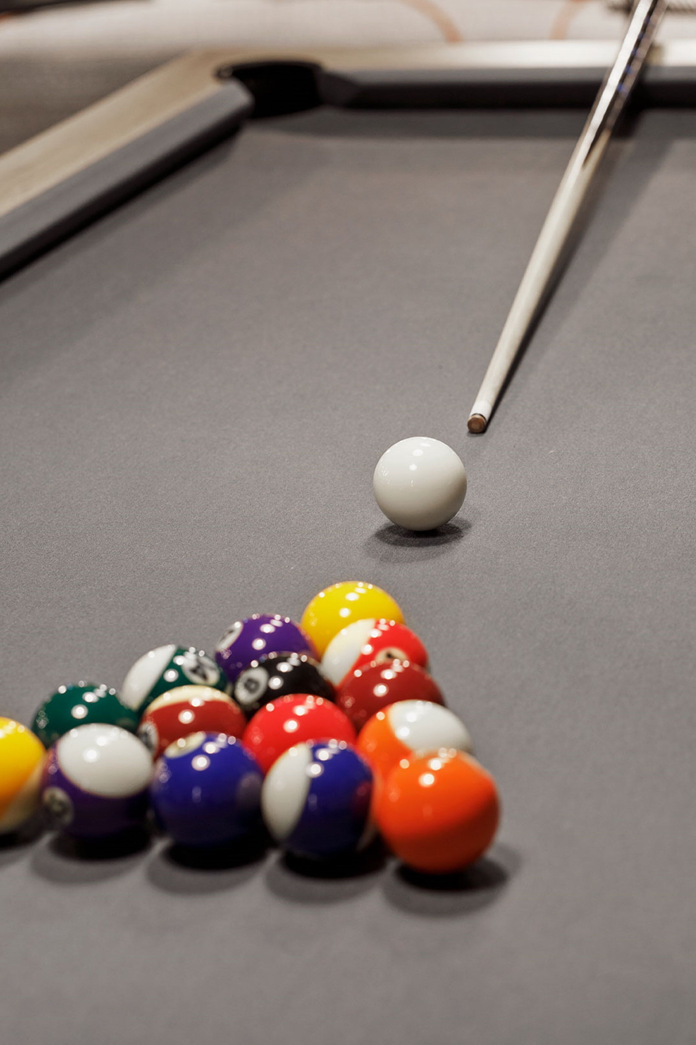 A pool table with a cue stick and a collection of billiard balls.