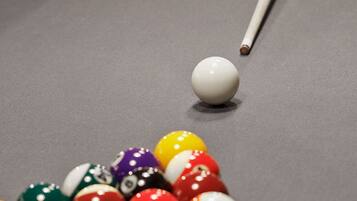 A pool table with a cue stick and a collection of billiard balls.