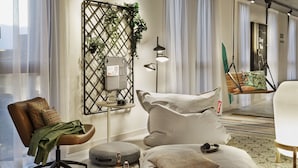 Une chambre à coucher moderne avec un lit, une chaise, un fauteuil suspendu et une petite table sur laquelle est posée une plante.