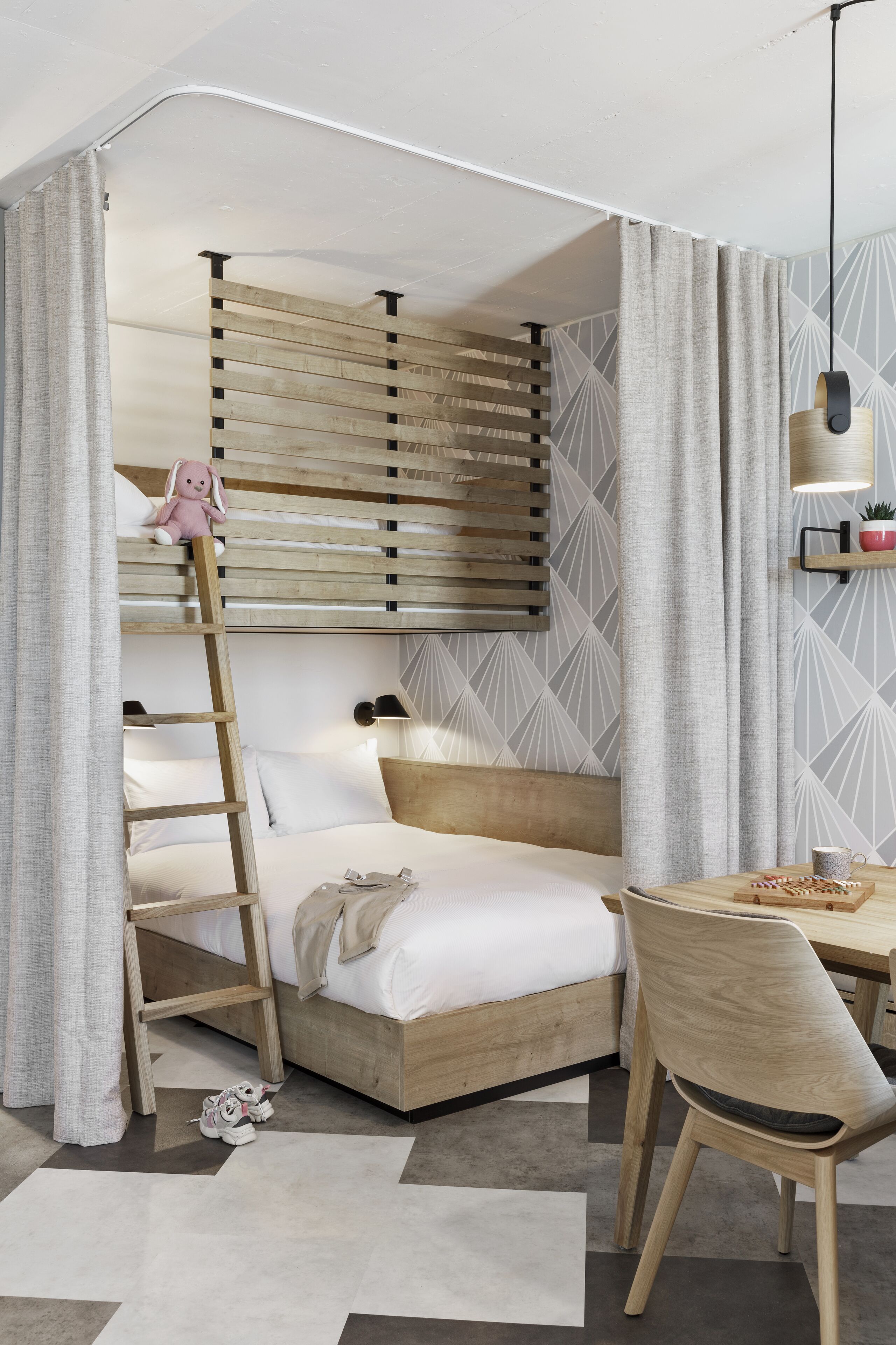 A bedroom with a bunk bed, a desk, a chair, and a ladder.