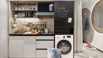Una cucina moderna con lavatrice integrata, mensole in legno e una lavagna con la definizione di bucato.