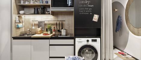 A modern kitchen with a built-in washing machine, wooden shelves, and a chalkboard with a laundry definition.