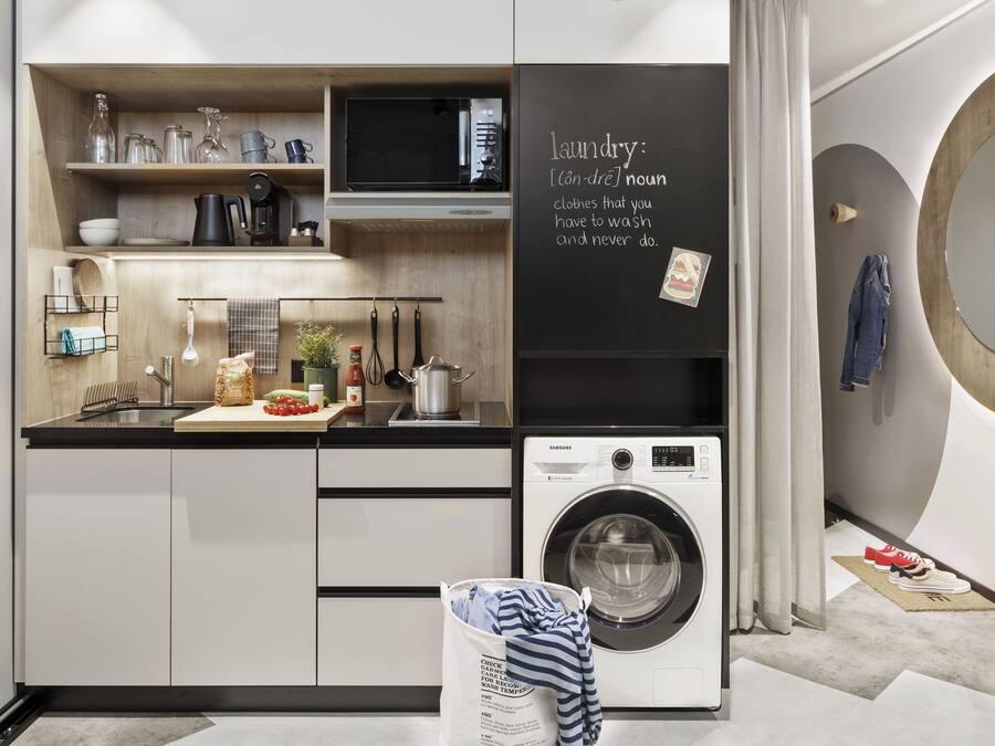 Una cucina moderna con lavatrice integrata, mensole in legno e una lavagna con la definizione di bucato.
