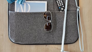 Un organizador de viajes con audífonos, gafas de sol, un control remoto y una billetera.