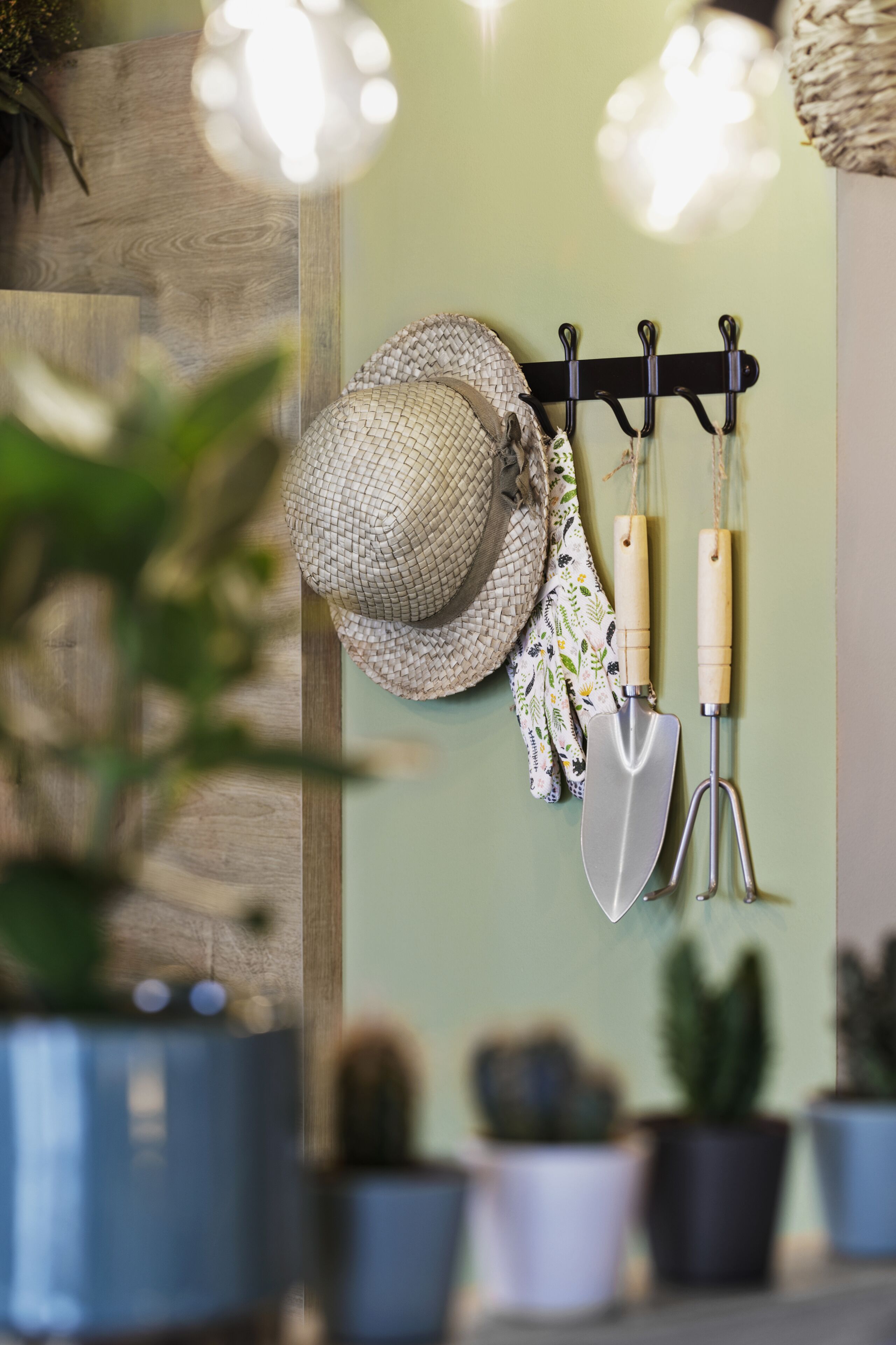 A wall-mounted rack with gardening tools and a hat.