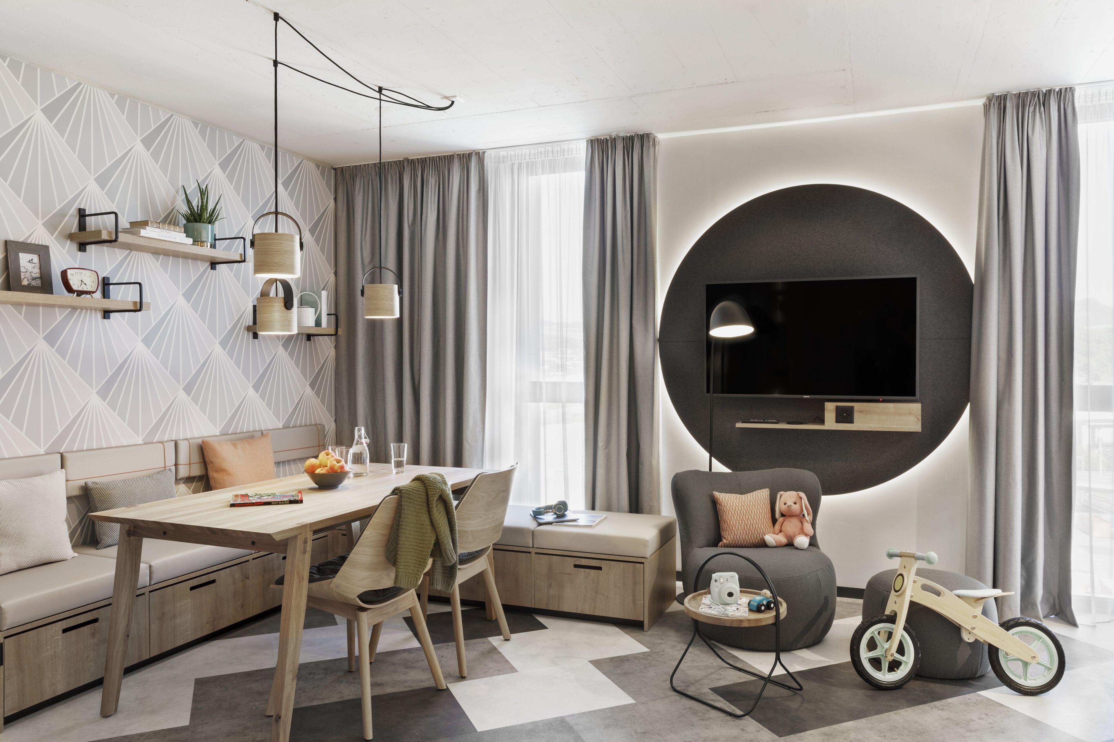 Una sala de estar moderna con un sofá, una mesa de comedor y un televisor montado en una pared circular.
