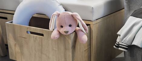 Una caja de madera con un peluche y un coche de juguete azul encima.