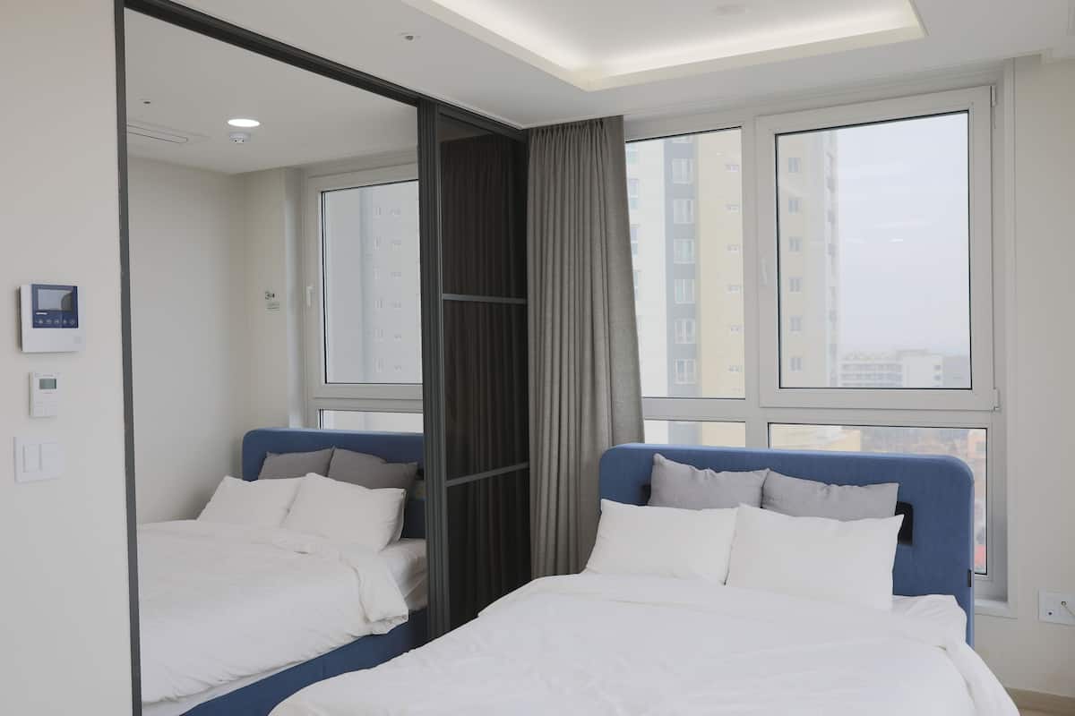 A hotel room with a large bed, a mirror, and a window with a city view.