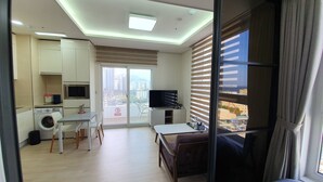 Ein modernes Hotelzimmer mit Balkon, Essbereich, Küche und Fernseher.