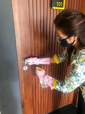 A person cleaning a wooden door with a yellow sign above it.