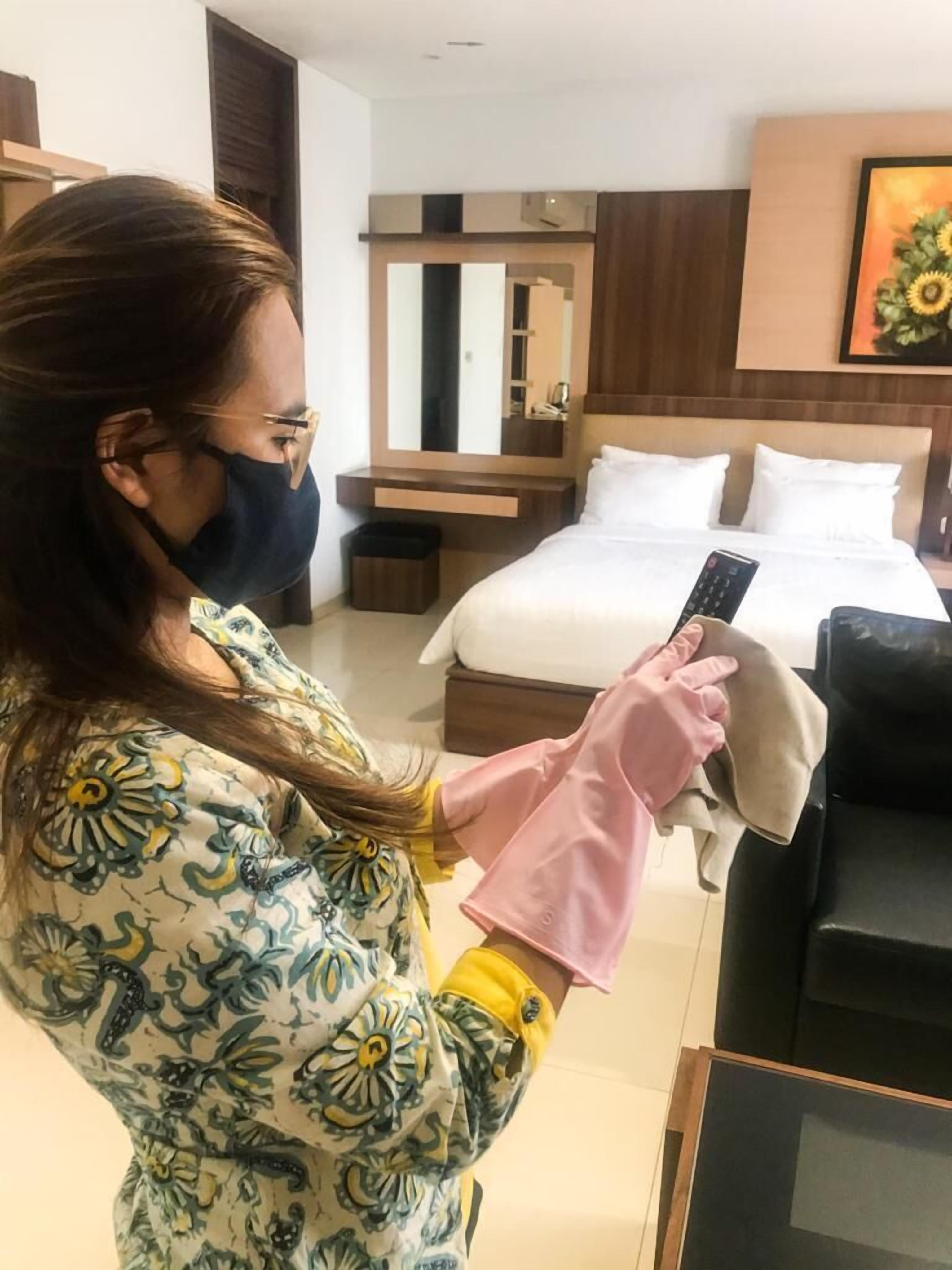 A hotel room with a bed, a bedside table, a mirror, and a painting on the wall.