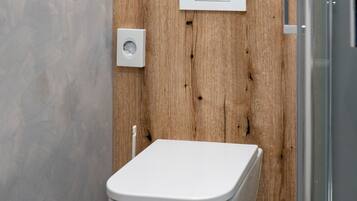 A modern bathroom with a wooden panel wall, a white toilet, and a glass shower enclosure.