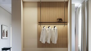A modern room with a built-in wardrobe, a bench with storage, and a hanging rack for clothes. - Hotel Am Park (Reichenbach im Vogtland)