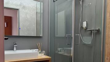 A modern bathroom with a glass-enclosed shower, a wooden vanity, and a large mirror.