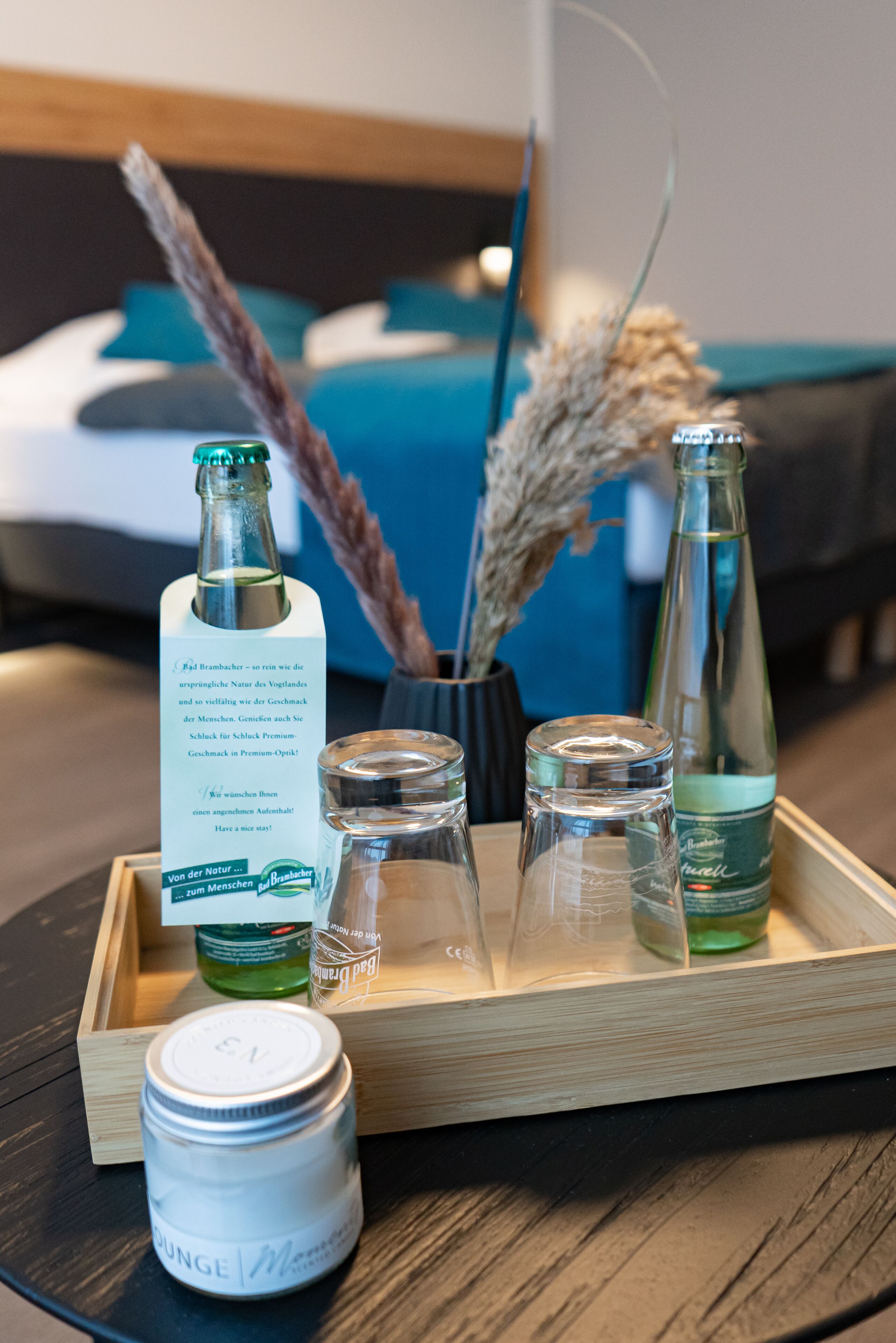 A tray with a bottle of Bad Brambach, a jar of massage oil, and two small glass bottles on a wooden table.