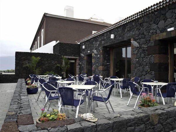 Een terras met stenen muren en metalen stoelen.