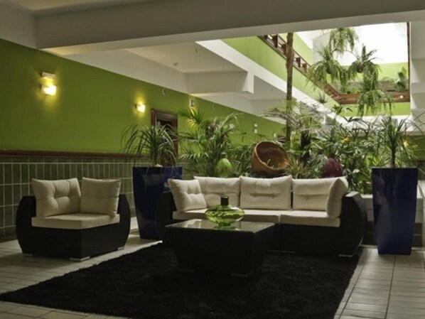 Eine Lobby mit grüner Wand, einer Treppe und einer Sitzecke mit schwarzem Teppich.