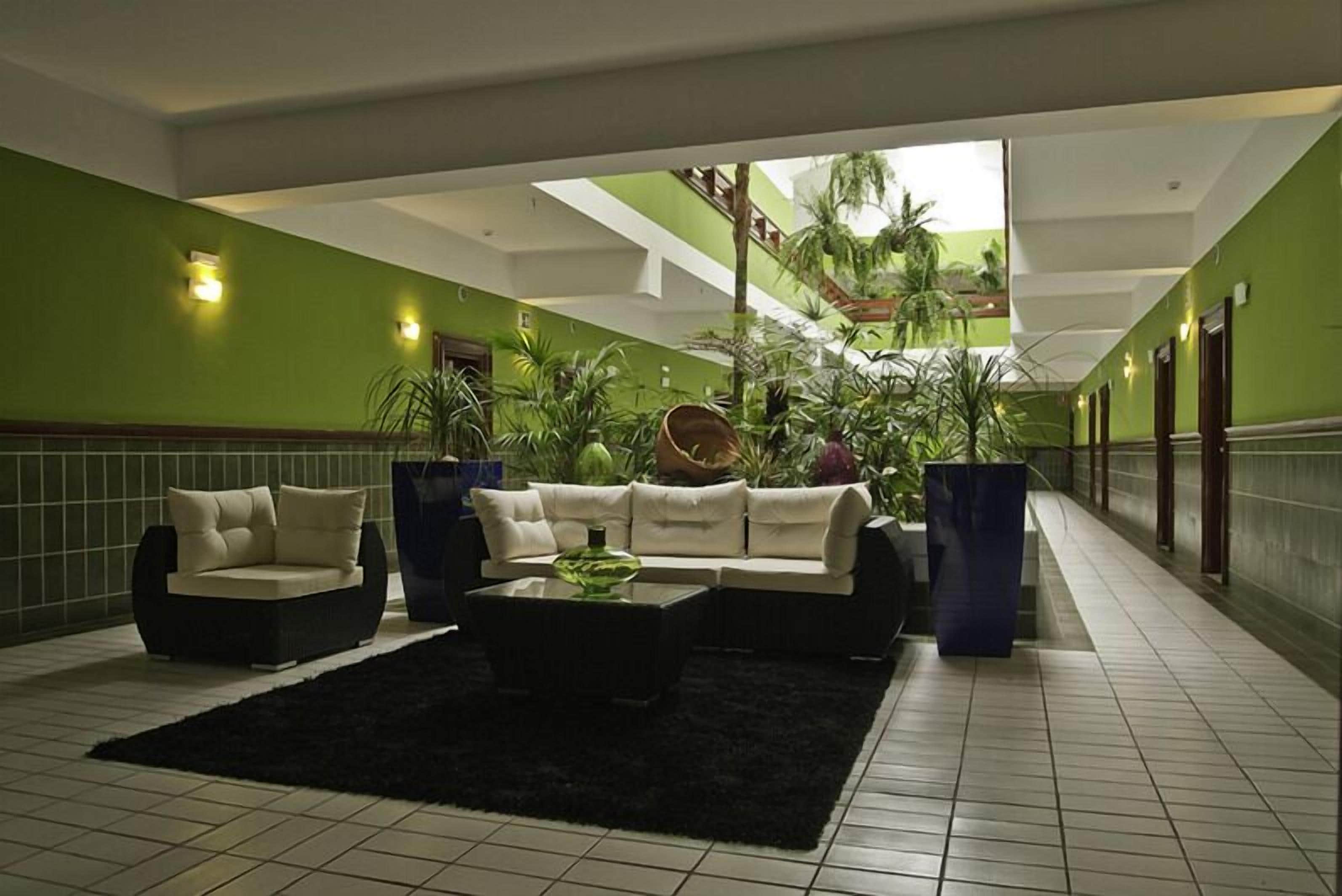 A lobby with a green wall, a black rug, a white sofa, and a coffee table.