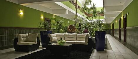 A lobby with a green wall, a black rug, a white sofa, and a coffee table.