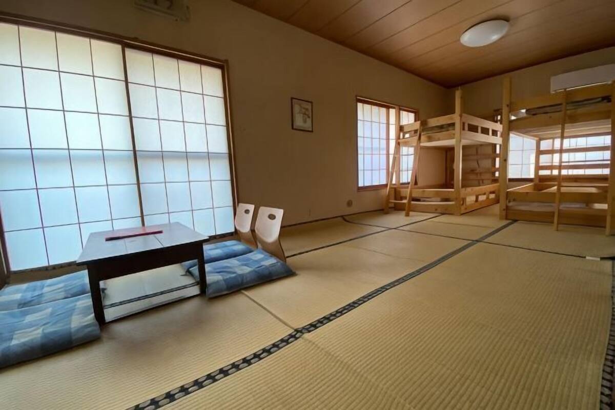 A tatami mat room with a low table, cushions, and a wooden bunk bed.
