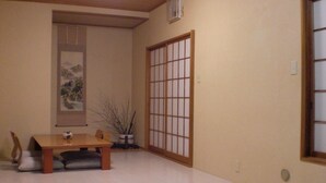 A room with a wooden dining table, chairs, a potted plant, a sliding shoji screen, and a framed artwork on the wall. - Numazu Ikkyuuan (Numazu)