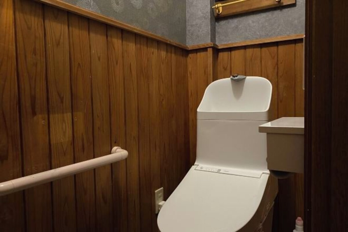 Un baño con paneles de madera, un inodoro blanco y un lavamanos blanco.