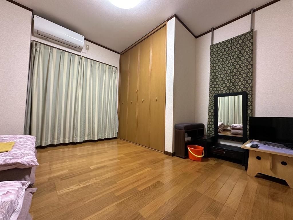 A room with a bed, a wardrobe, a television, and a small table.