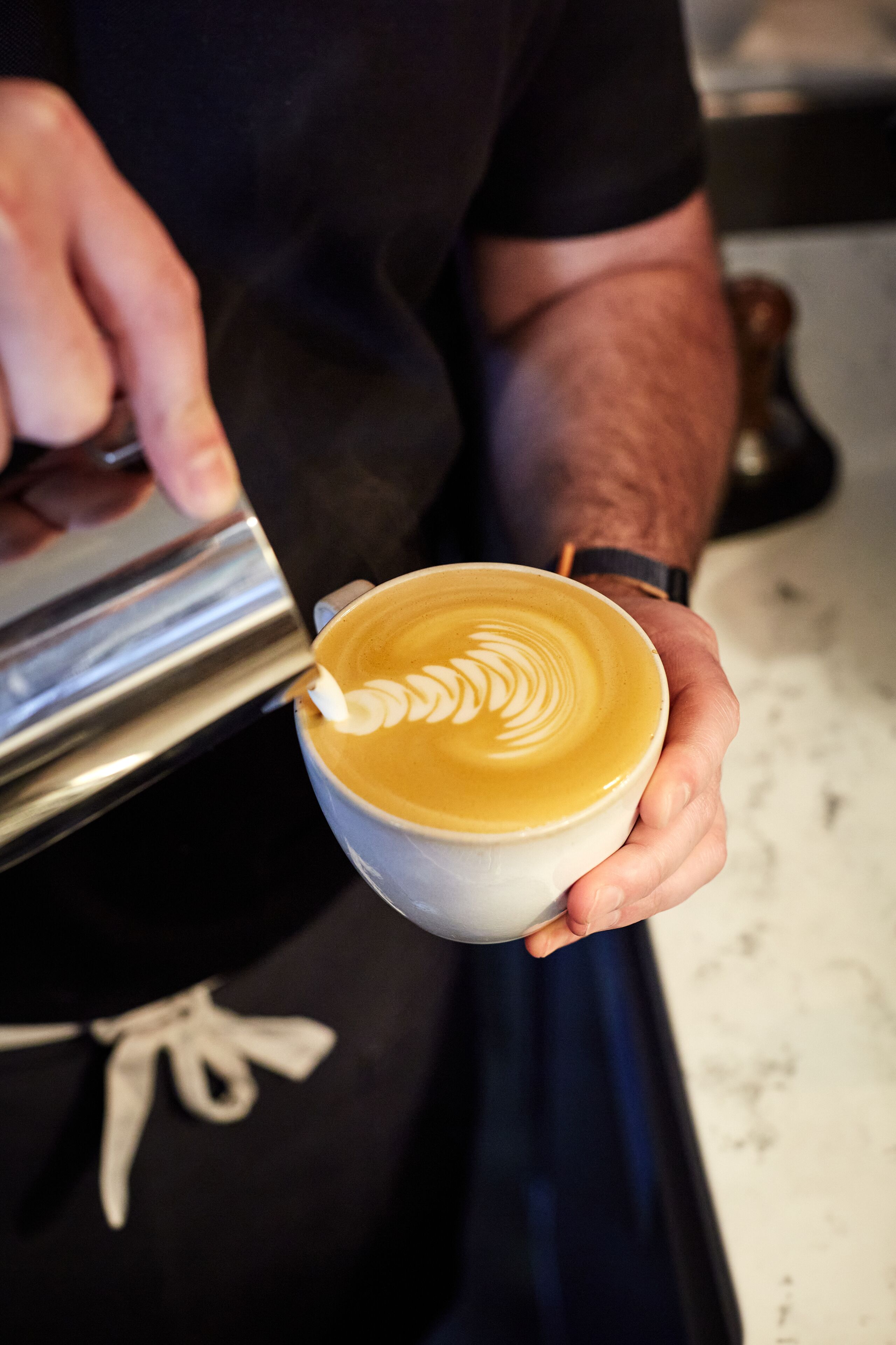 Una persona che tiene in mano una tazza di caffè con decorazione in schiuma di latte.