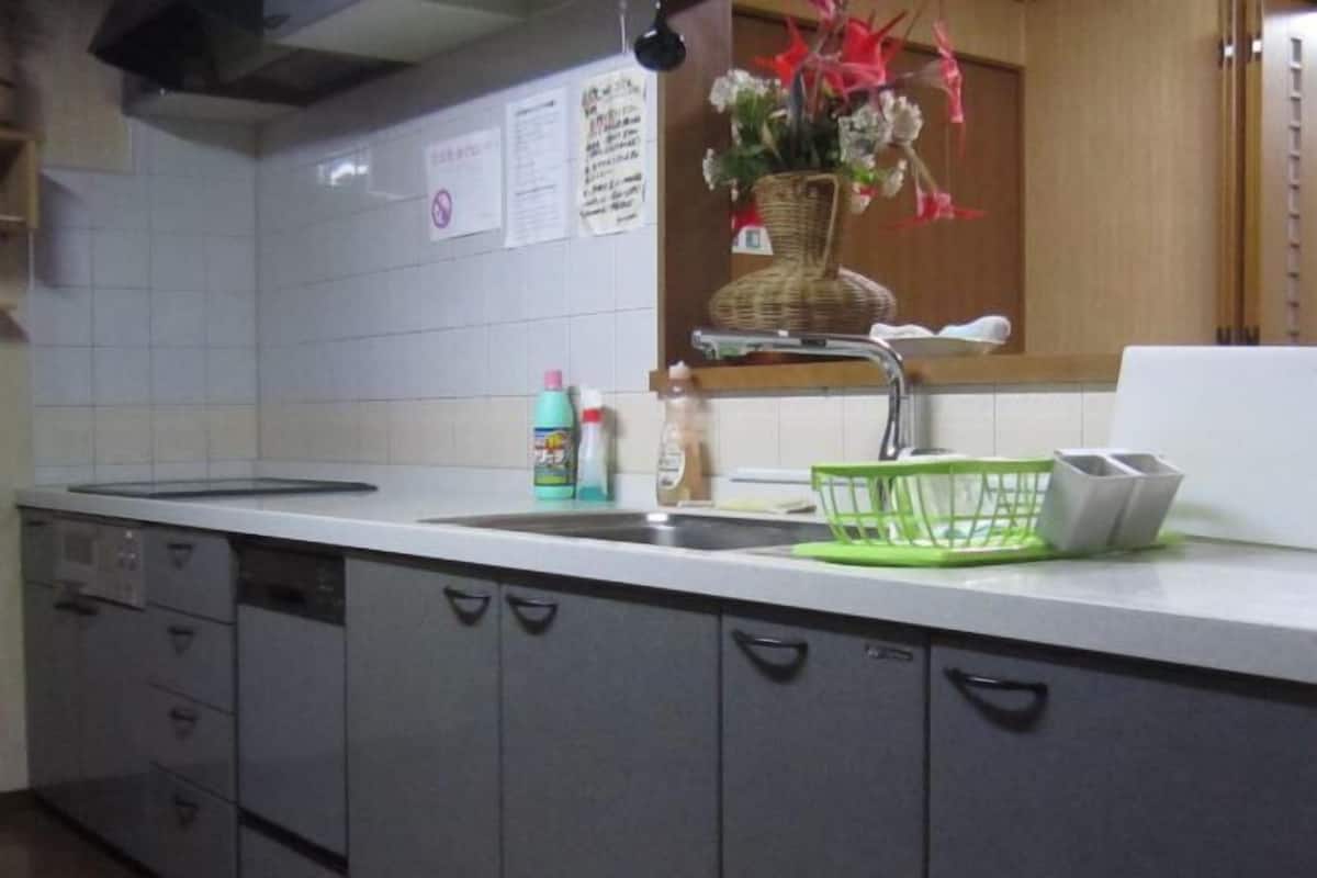 Cozinha com bancada branca, pia, escorredor de louça verde e armários.