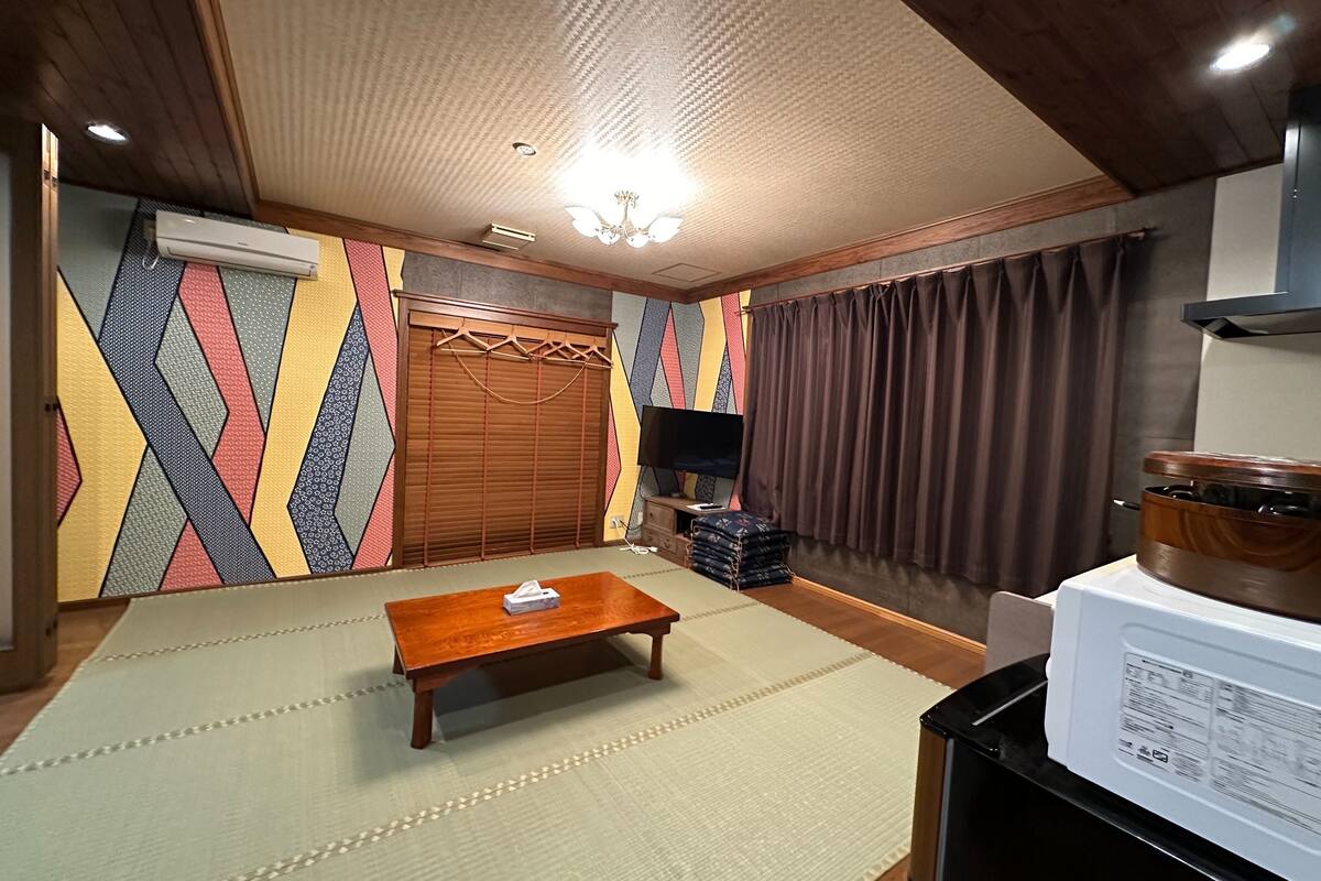 Quarto com teto de madeira, televisão, armário de madeira, micro-ondas e parede estampada.