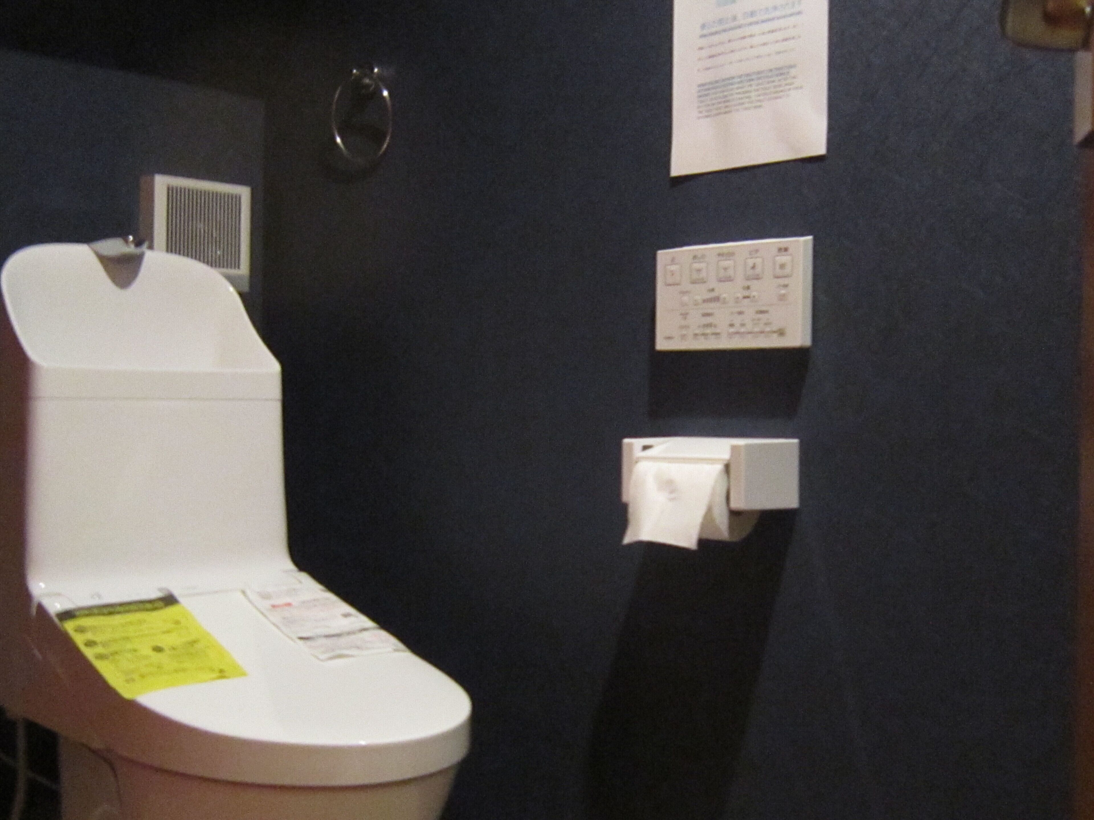 A bathroom with a white toilet, a paper towel dispenser, and a wall-mounted paper towel holder.