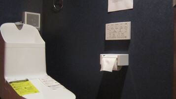A bathroom with a white toilet, a paper towel dispenser, and a wall-mounted paper towel holder.