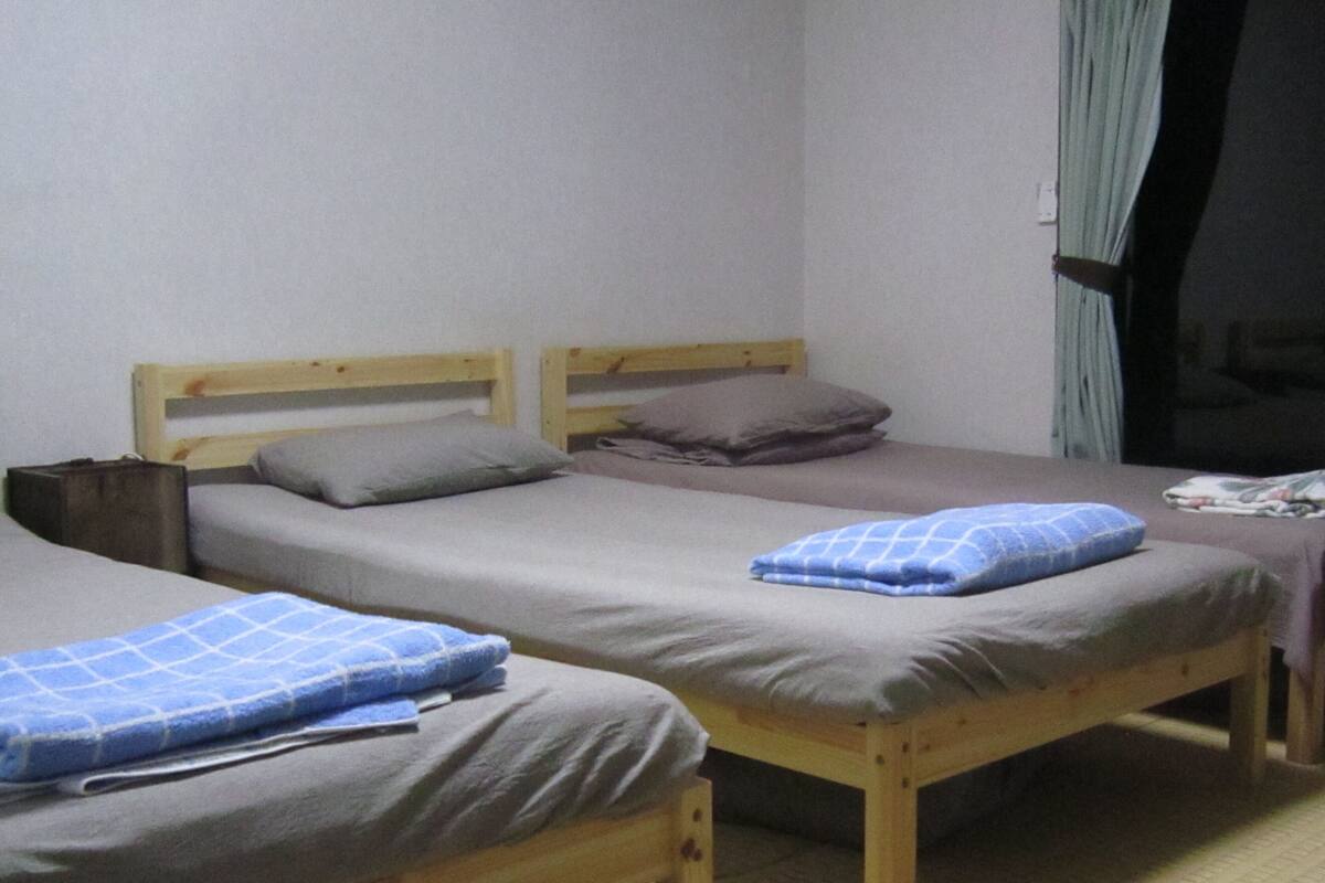 Um quarto com duas beliches de madeira, cada uma com colchão e almofadas.