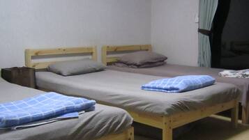 A room with two wooden bunk beds, each with a mattress and pillows.