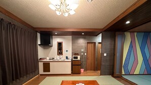 Une pièce avec une table en bois, un coin cuisine, un miroir et un mur décoré de motifs.