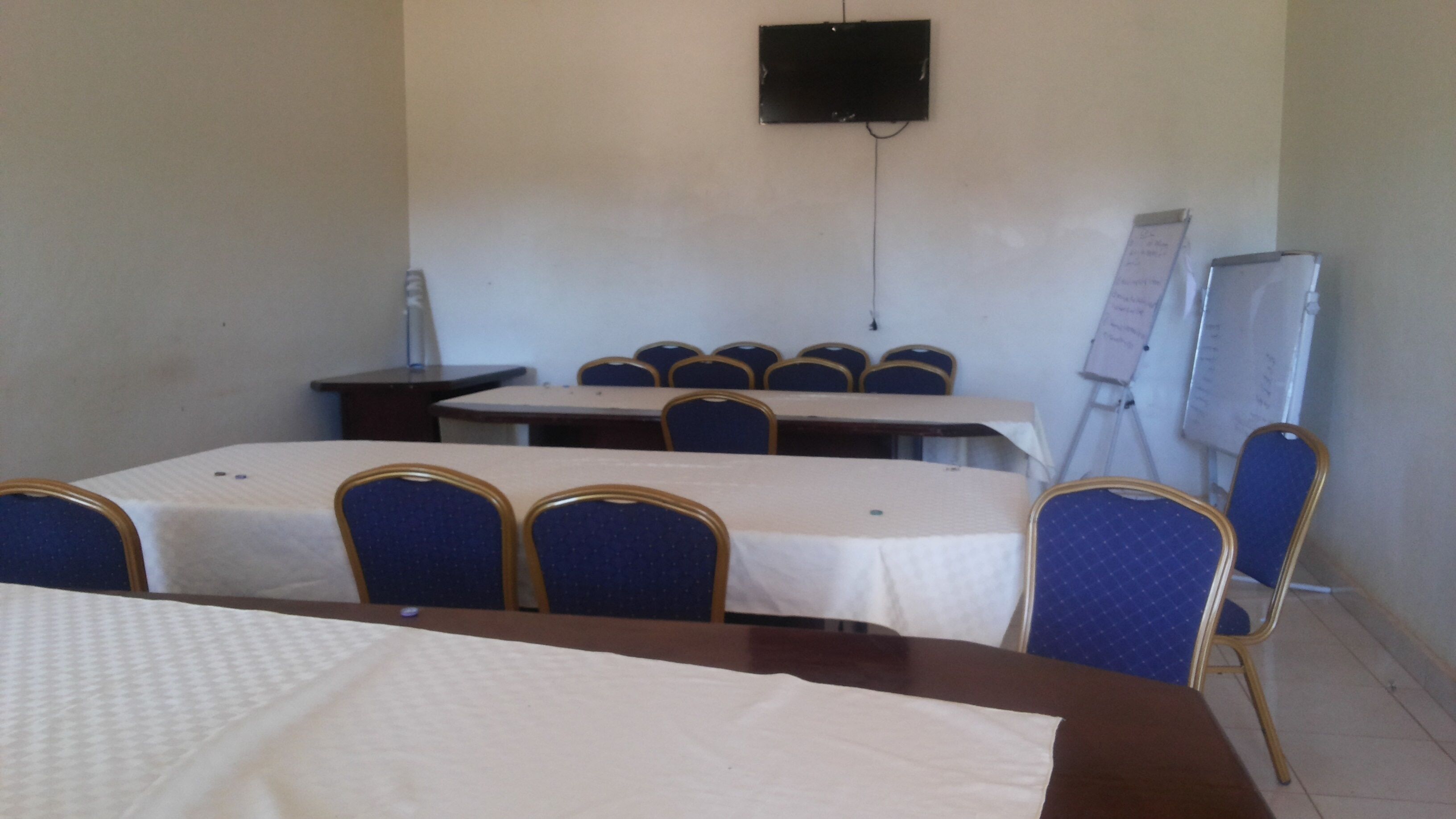 A conference room with tables and chairs, a whiteboard, and a projector screen.