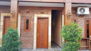 Un bâtiment en briques doté de deux portes en bois, d’une petite fenêtre et d’un climatiseur fixé au mur.