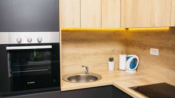 Una cocina moderna con horno Bosch, un lavabo, un hervidor y armarios de madera.