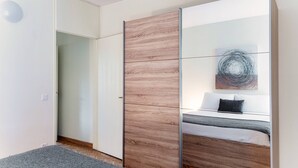 A modern bedroom with a bed, a wardrobe, and a mirror. - Pazzallo Apartments (Lugano)