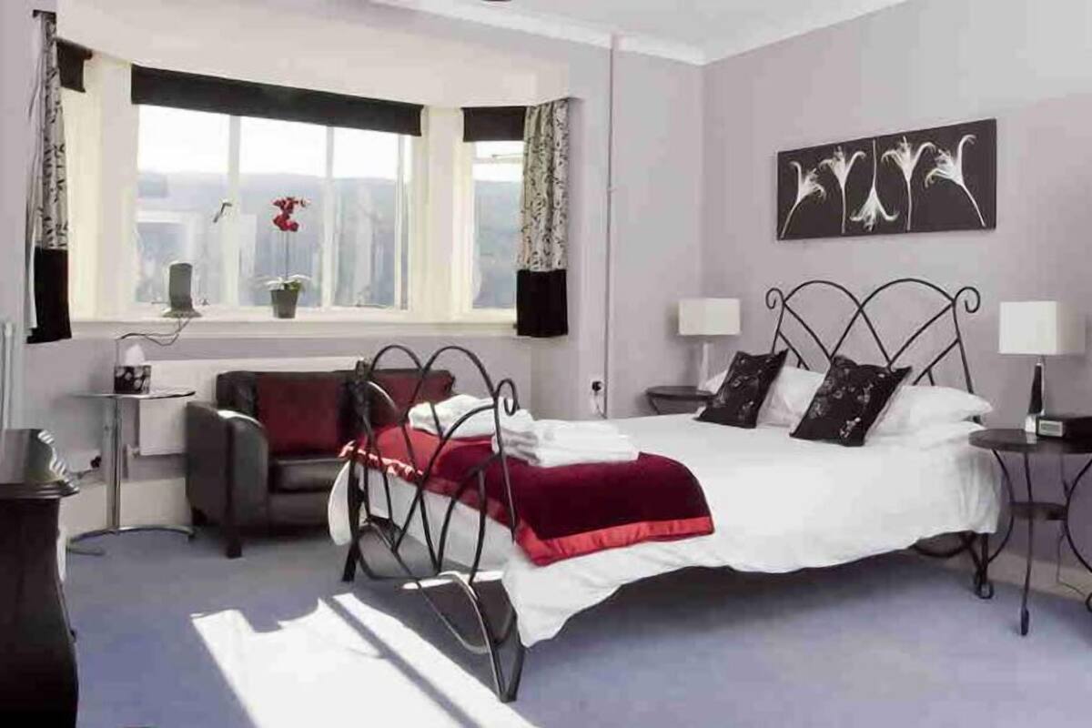 A bedroom with a bed, bedside tables, a window, and a door.