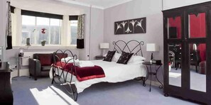 A bedroom with a bed, bedside tables, a window, and a door. - Glenurquhart House (Inverness)