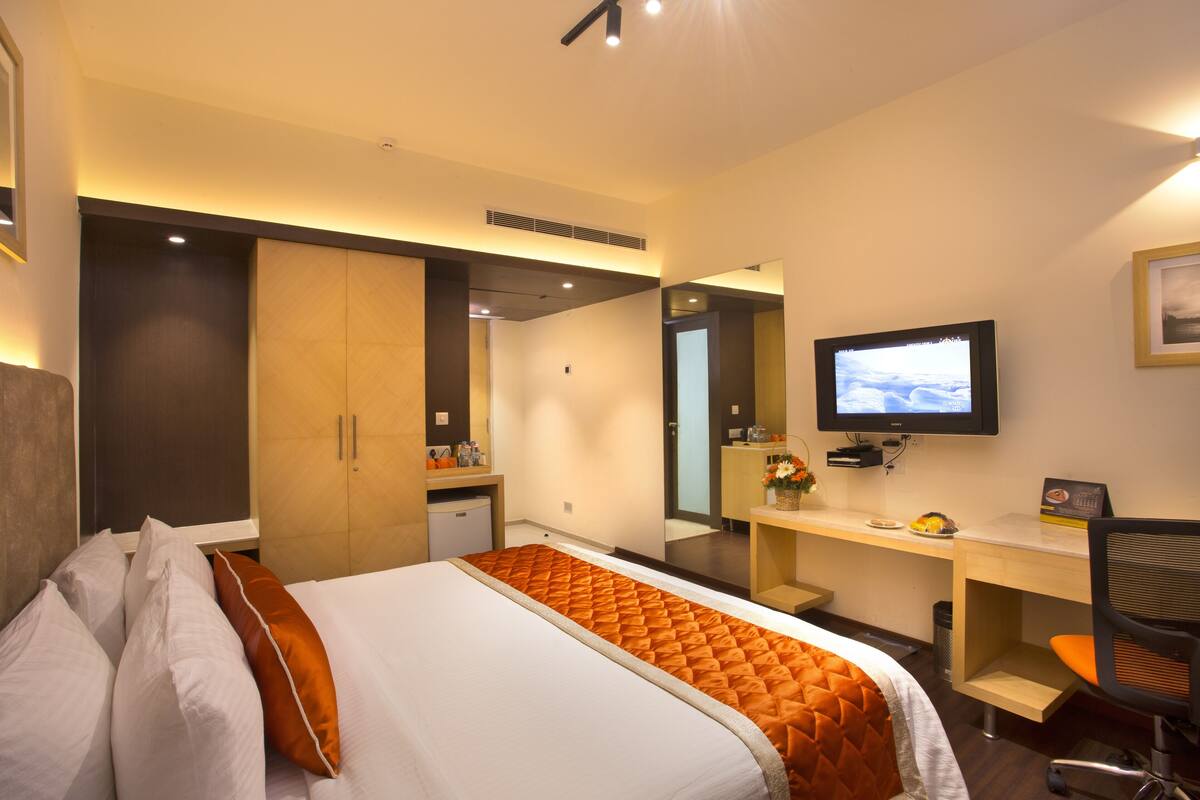 A hotel room with a bed, a desk, a television, and a mirror.