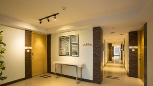 Un moderno vestíbulo de hotel con un mostrador de recepción, obras de arte enmarcadas y un largo pasillo que da a otras habitaciones.