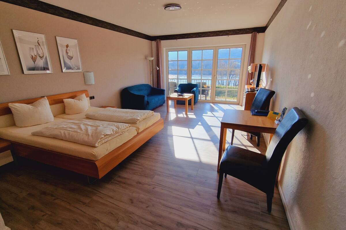 A hotel room with a large bed, a desk, and a chair. There are three framed pictures on the wall.