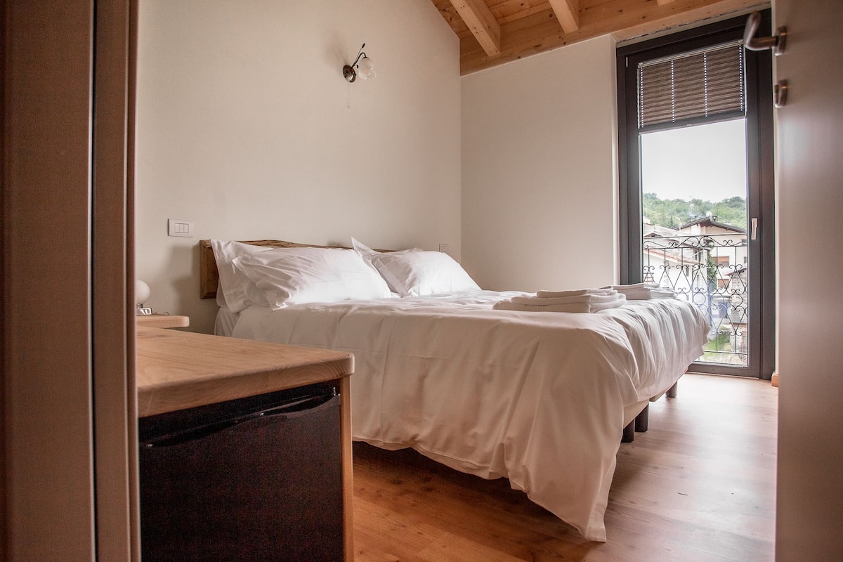 Ein Schlafzimmer mit einem Bett, einem Holztisch und einem Fenster mit Blick auf Gebäude.
