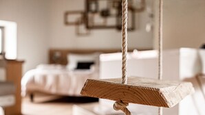 Un arbre à chat en bois avec une corde, dans une pièce où se trouvent un lit et un bureau.