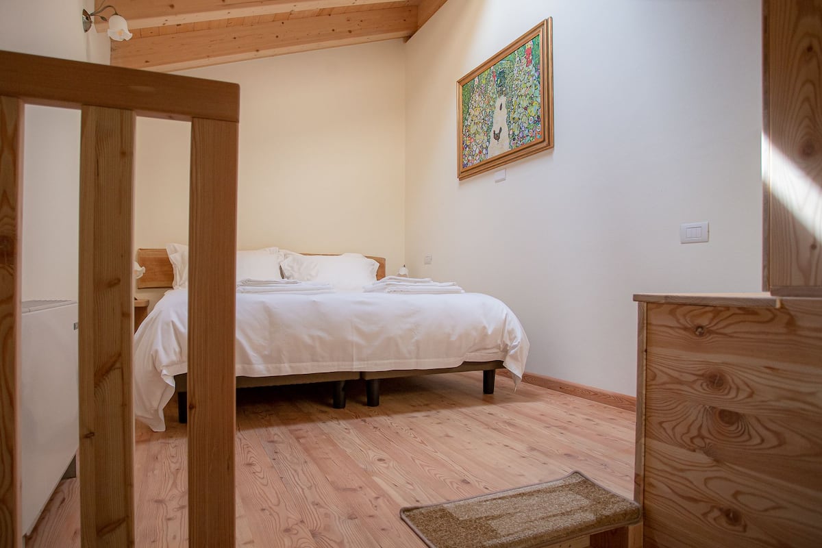 Ein Schlafzimmer mit einem hölzernen Bett, einem Nachttisch, einer hölzernen Kommode und einem Gemälde an der Wand.